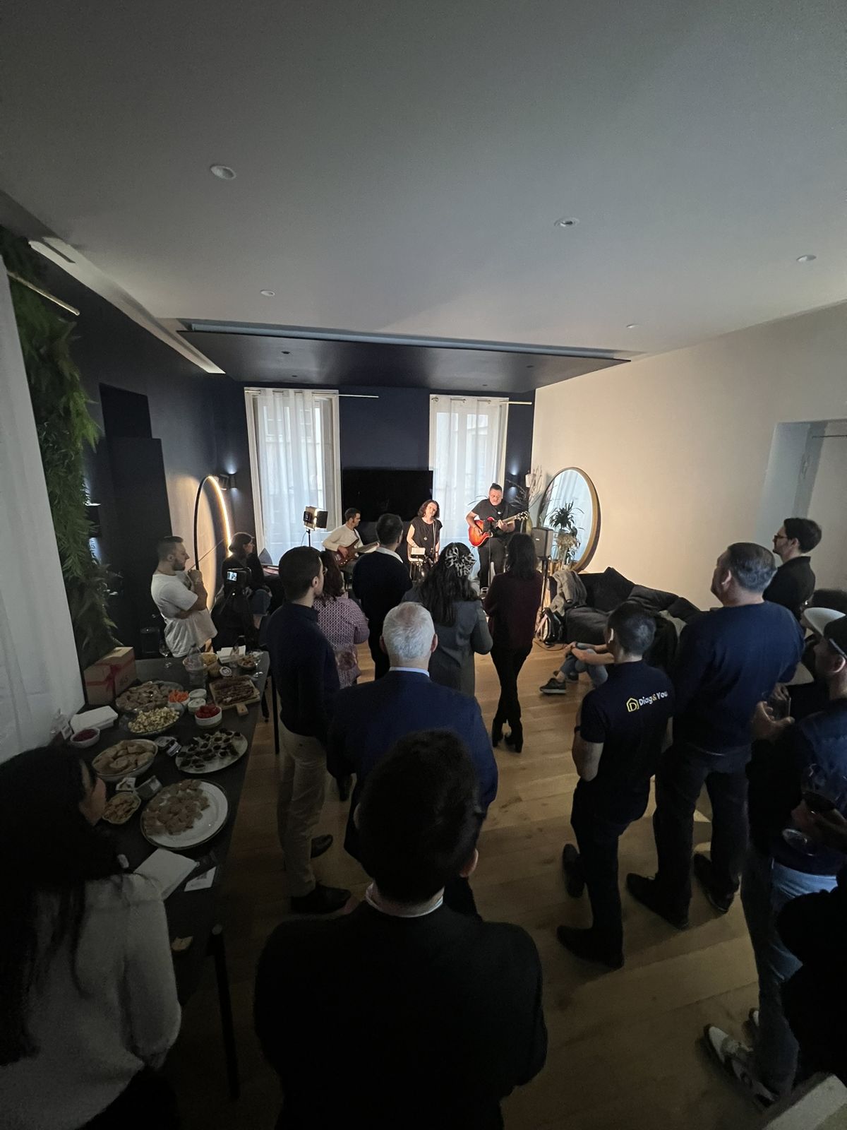 Concert privé dans le salon de la WinHome à Lyon : un groupe joue devant les invités, buffet sur la grande table