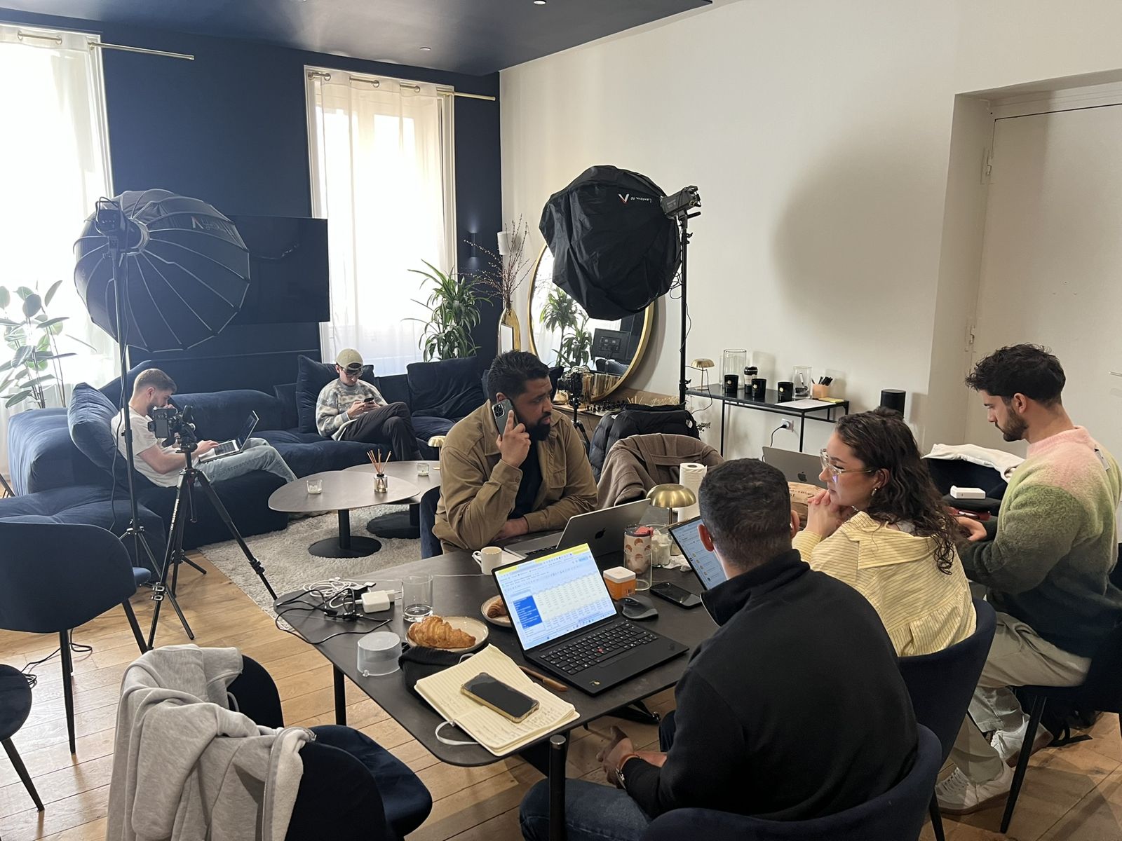 Une équipe de start-up travaille autour de la grande table de la WinHome pendant que l'équipe photo s'installe dans le salon